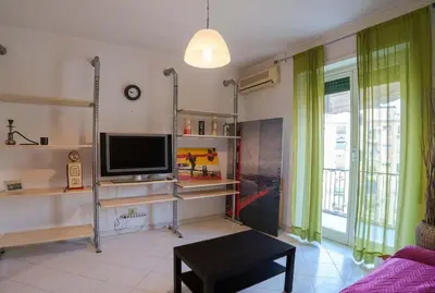 a living room with a flat screen tv and green curtains at Hostme Luminoso Appartamento Metro Marconi in Rome