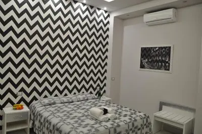 a bedroom with a bed with a black and white checkered wall at Il Corso Suite in Rome