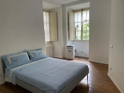 a bedroom with a bed with blue sheets and two windows at Deromatality Vaticano Piazza di Spagna Colosseo in Rome