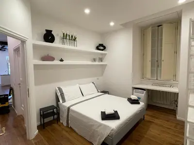 a white bedroom with a bed and a window at Deromatality Vaticano Piazza di Spagna Colosseo in Rome