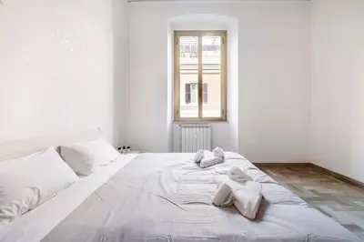a bedroom with a large bed with white sheets at Casa amoR in Trastevere in Rome