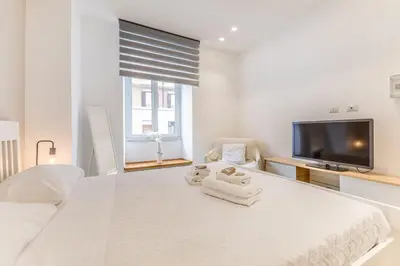 a white bedroom with a large bed and a flat screen tv at Principe Umberto Suite - Stazione Termini in Rome