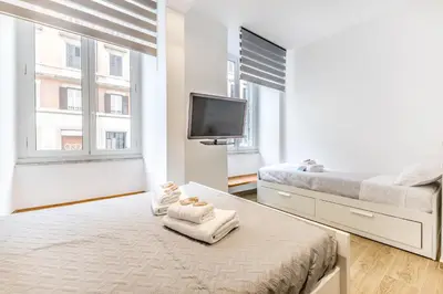a white room with two beds and a flat screen tv at Principe Umberto Suite - Stazione Termini in Rome