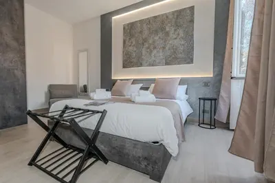 a bedroom with a large bed and a chair at Domus Æterna - Re di Roma in Rome