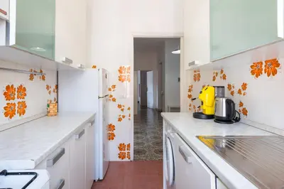 a kitchen with white counters and orange flowers on the wall at Casa di Marianna e Vittorio al Gemelli in Rome