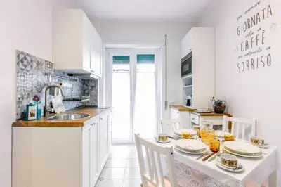 a white kitchen with a table with plates on it at Il rifugio dei nonni by Rentbeat in Rome