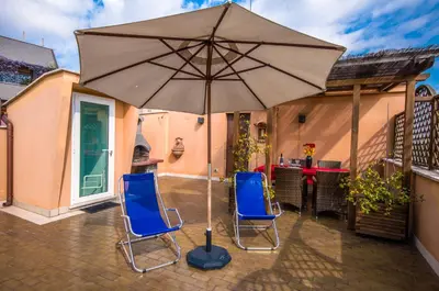 two blue chairs and an umbrella on a patio at Vatican Penthouse Near S.Peter's Square in Rome