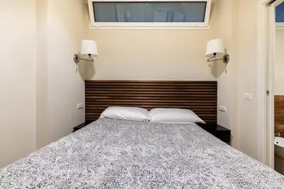 a bedroom with a bed with a wooden headboard and two lamps at alloggio la carica dei 101 in Rome