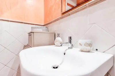 a white bathroom with a sink and a cup on it at La Rosa Dei Papi in Rome