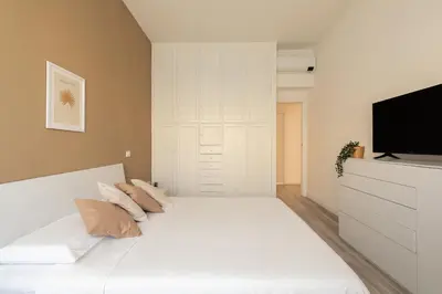 a bedroom with a white bed and a flat screen tv at Sweet Rhome to Colosseum in Rome