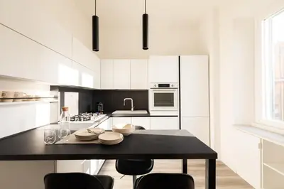 a kitchen with white cabinets and a black table with chairs at Sweet Rhome to Colosseum in Rome