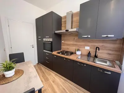 a kitchen with black cabinets and a sink and a table at PyramidHouse Rome - Apartment 100mq with View - 2km from the Colosseum in Rome