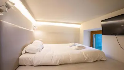 a bedroom with a white bed with a flat screen tv at EasyTopStay - Trastevere Cozy Nest with Terrace in Rome