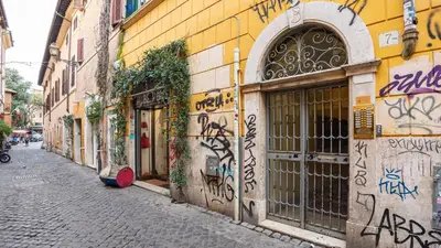a street with graffiti on the side of a building at EasyTopStay - Trastevere Cozy Nest with Terrace in Rome