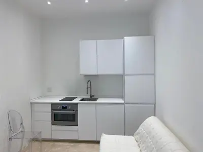 a kitchen with white cabinets and a sink and a couch at Amazing Cozy Piazza Venezia in Rome
