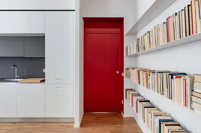 a red door in a hallway with bookshelves at GIULIANA Boutique Apartment in Rome