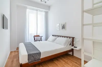 a white bedroom with a bed and a chair at GIULIANA Boutique Apartment in Rome