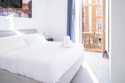 a white bedroom with a white bed and a balcony at Élite Vatican Refuge in Rome