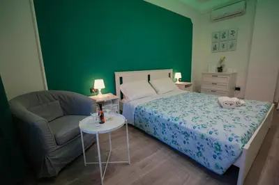 a green bedroom with a bed and a chair at House Appio Latino Roma in Rome
