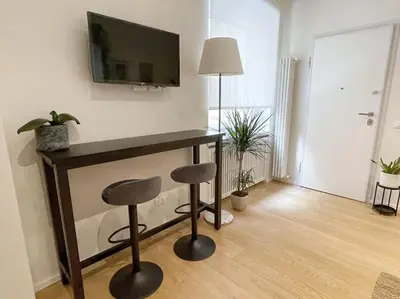 a living room with a desk with two stools and a television at STUDIO4 ROMA in Rome