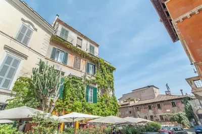 a building covered in ivy with tables and umbrellas at L'antico borgo di Trastevere III in Rome