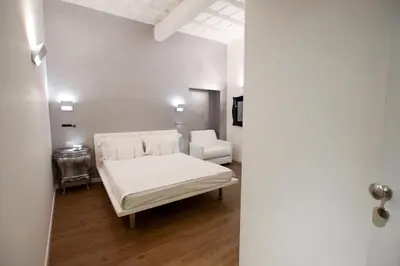 a bedroom with a white bed and a chair at Navona Secret Stay Guest House in Rome