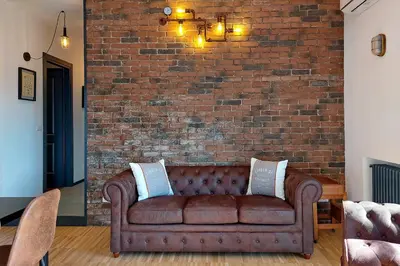 a brown couch sitting in front of a brick wall at YCH-Trilocale stile Industriale in Rome