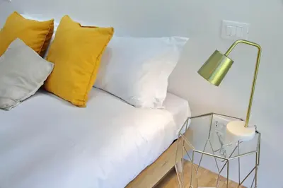 a white couch with yellow pillows and a lamp at YCH TRILOCALE FINEMENTE ARREDATO VICINO ALLA METRO in Rome