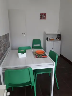 a kitchen with a table and four green chairs at La Piccoletta di Garbatella in Rome