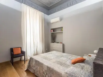 a bedroom with a bed and a chair and a window at Luxury Fori Imperiali Flat in Rome