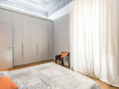a bedroom with a bed and a chair and a window at Luxury Fori Imperiali Flat in Rome