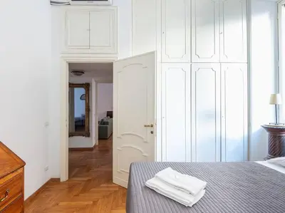 a bedroom with a bed with white cabinets and a mirror at Giulia Luxury Two Bedroom Apartment in Rome