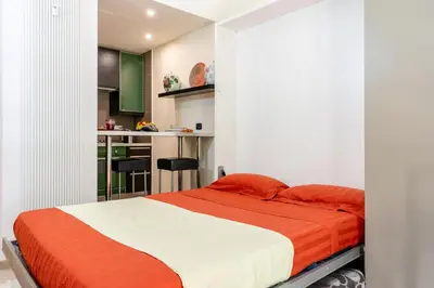 a bedroom with a large bed and a kitchen at Appartamento Celio in Rome