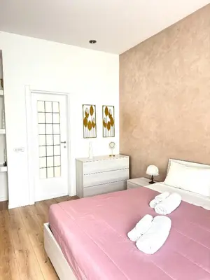 a bedroom with a pink bed with two towels at Maddalena Means Home in Rome