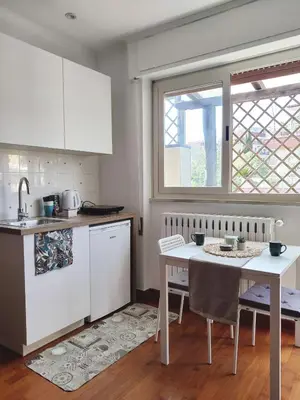 a kitchen with white cabinets and a table and a window at Bright Penthouse 2 M stops from Vatican Museums in Rome