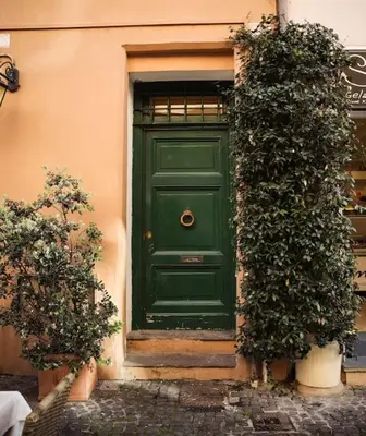 a green door on a building with two bushes at Dolce Casa in San Pietro in Rome