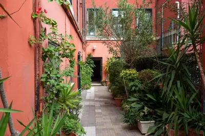 an alley with plants and a pink building at Aventino apartment in Rome