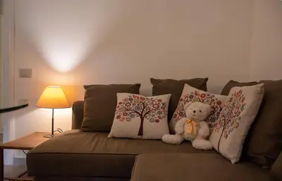 a teddy bear sitting on a couch with pillows at Aventino apartment in Rome