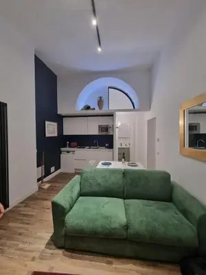 a living room with a green couch and a kitchen at Piccolo Principe Suite in Rome