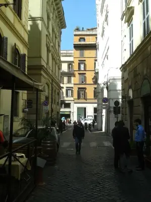 a group of people walking down a street with buildings at Barberini 360 in Rome