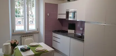 a kitchen with white cabinets and pink walls and a table at Trastevere Residenze in Rome