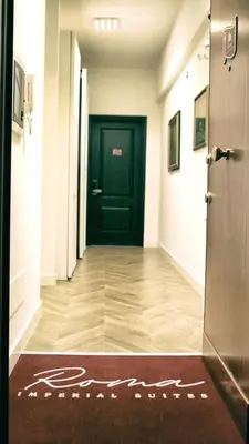 a hallway with a black door and a welcome mat at Roma Imperial Suites in Rome