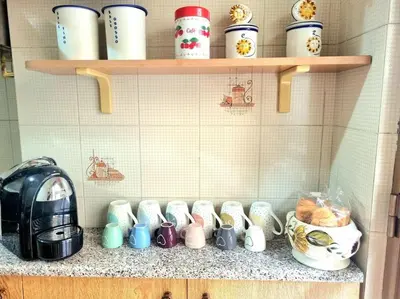 a bunch of coffee cups on a shelf in a kitchen at Appartamento Antico AMOR in Rome