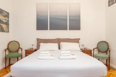 a bedroom with a large white bed with two chairs at Skyline Penthouse with Private Rooftop in Rome