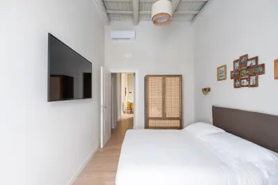 a white bedroom with a bed and a flat screen tv at Corso Caesar Suites in Rome