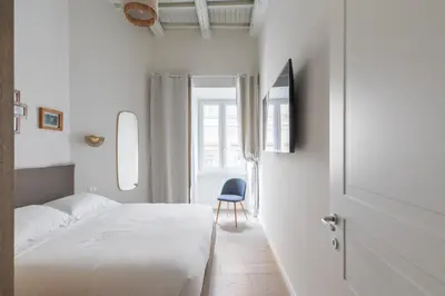 a bedroom with a white bed and a blue chair at Corso Caesar Suites in Rome