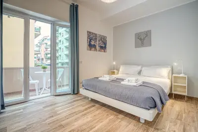 a white bedroom with a bed and a large window at Emily Valles Apartment Saint Peter's in Rome