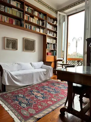 a living room with a bed and a table and bookshelves at Colosseum Luxury Apartment in Rome