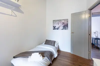a white bedroom with a bed and a painting on the wall at La Locanda Bertani in Rome
