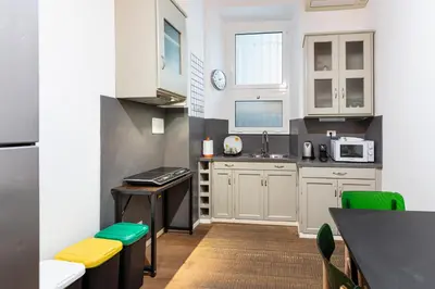 a kitchen with white cabinets and green accents at La Locanda Bertani in Rome